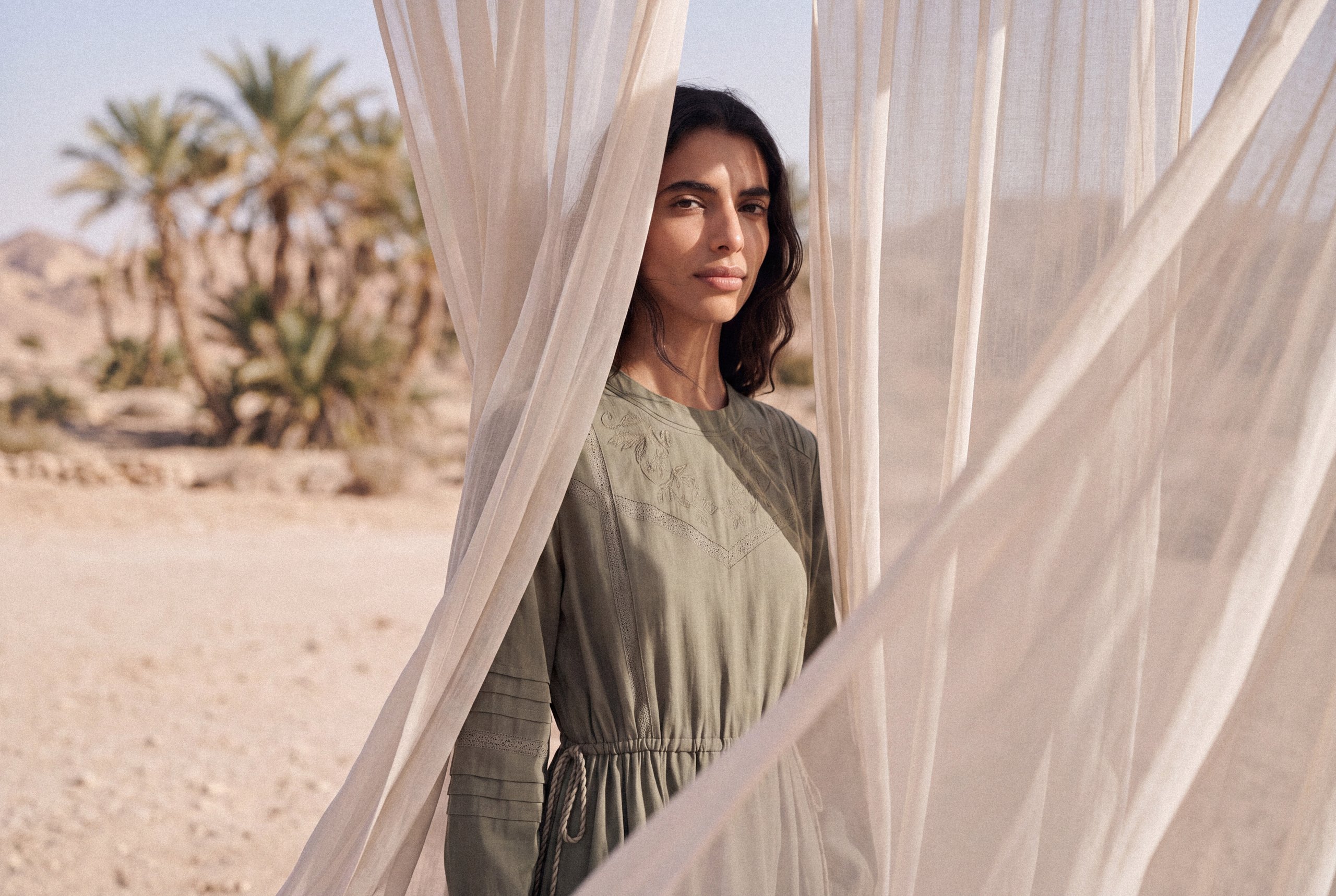 KINSHIP campaign: model in a green dress framed by sheer curtains