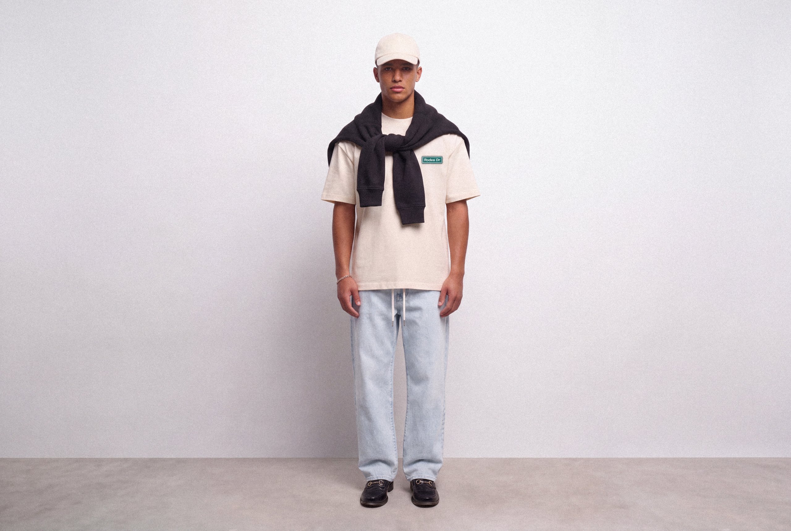 Needleworks campaign: model in a cream T-shirt with a dark sweatshirt and light jeans