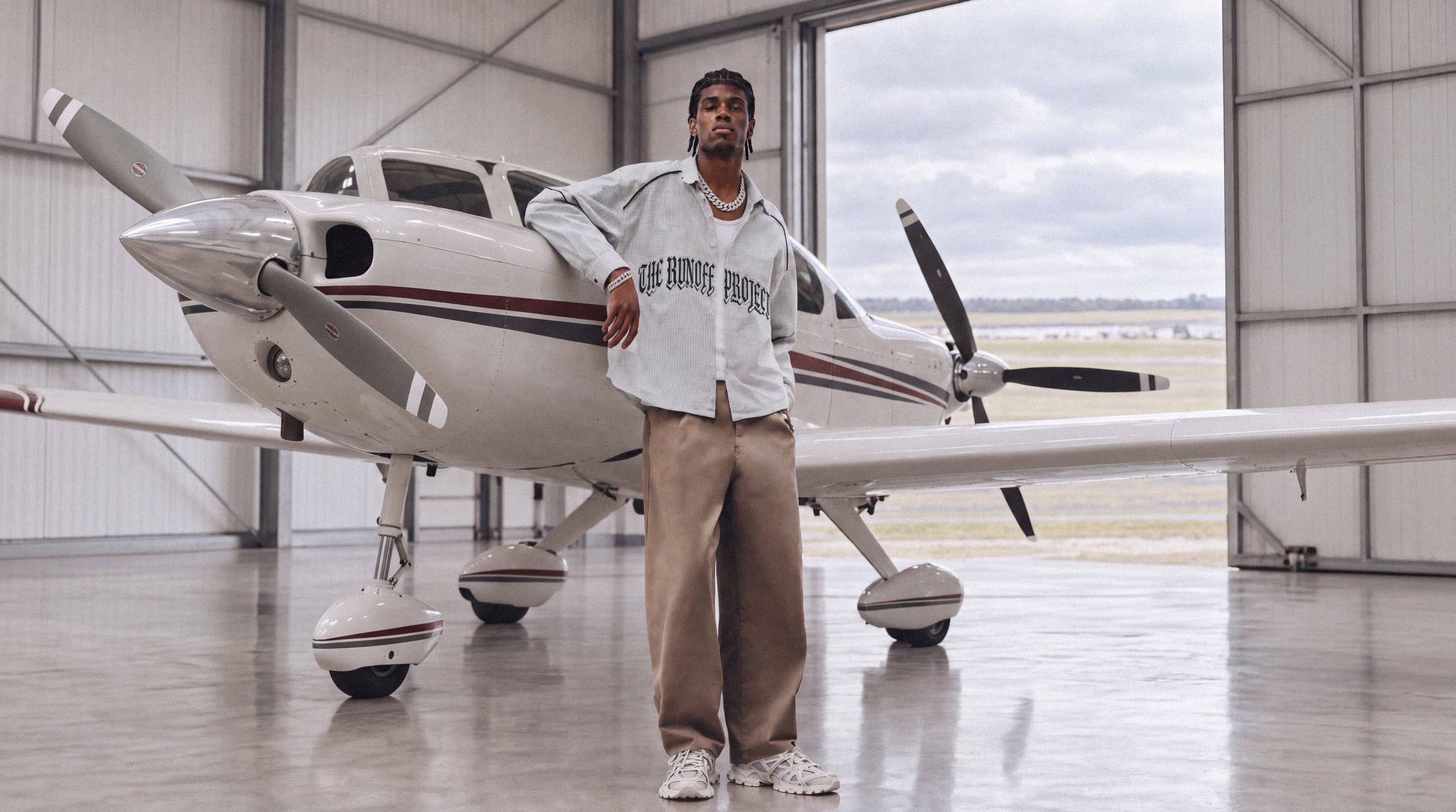 TRP campaign: model wearing a light shirt beside an aircraft in a hangar
